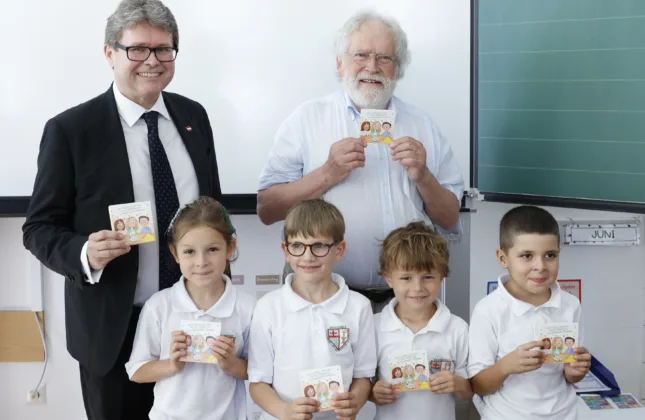 Professor Zeilinger und Bundesminister Polaschek mit vier Kindern, alle halten ein Pixi-Buch in Händen.